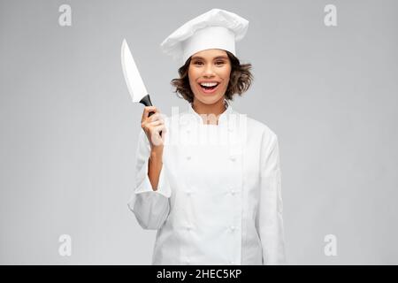chef femminile sorridente in toque con coltello da cucina Foto Stock