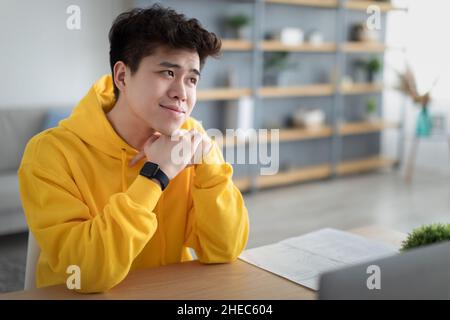 Uomo asiatico tranquillo seduto alla scrivania e sognare Foto Stock