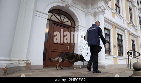 Magdeburg, Germania. 10th Jan 2022. Un funzionario di polizia indaga sull'esterno del parlamento di stato Sassonia-Anhalt con un cane da cecchino esplosivo. L'edificio principale del parlamento di Sassonia-Anhalt è stato evacuato. In precedenza, una minaccia di bomba era stata ricevuta per posta elettronica tramite una cassetta postale centrale, come ha confermato una portavoce del parlamento alla Deutsche Presse-Agentur. Credit: Ronny Hartmann/dpa/Alamy Live News Foto Stock