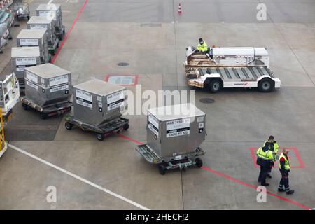 L'equipaggio di terra o i movimentatori di bagagli con l'attrezzatura di supporto a terra dell'aeroporto attendono di caricare i contenitori di merci su un aereo / aereo / aereo all'aeroporto di Ginevra, Svizzera. (128) Foto Stock