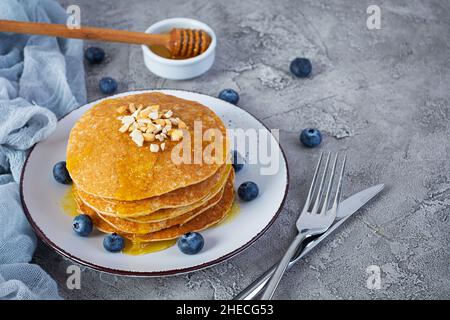 Deliziose frittelle fatte in casa con miele e mirtilli. Colazione gustosa con crepes Foto Stock