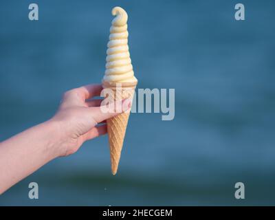 La donna tiene un gustoso gelato sulla spiaggia. Foto Stock