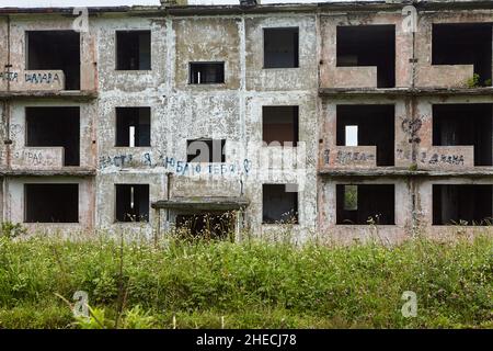 Facciata di una casa abbandonata a 3 piani con alberi in crescita proprio sulla parte superiore dell'edificio. Foto Stock