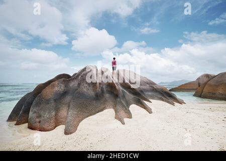 Uomo in piedi sulla roccia e guardando la vista. Turista solitario godendo di calma su idilliaca spiaggia in Seychelles. Foto Stock