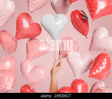 palloncini a forma di cuore che galleggiano nell'aria e una mano che ne tiene uno. concetto di san valentino, l'amore è nell'aria, trovare l'amore, le coppie e il matrimonio. 3d rendering Foto Stock