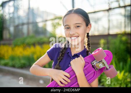 Sorridendo felice caucasica ragazza skateboarder guardando avanti Foto Stock