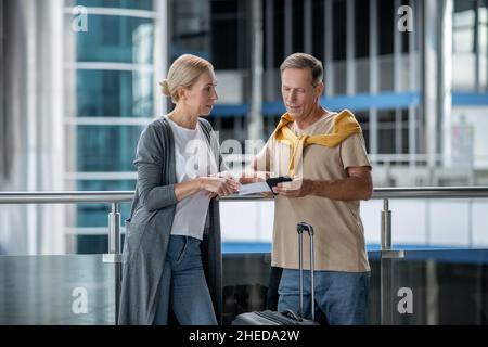 Passeggero dell'aeroporto che parla con un maschio con documenti di viaggio Foto Stock