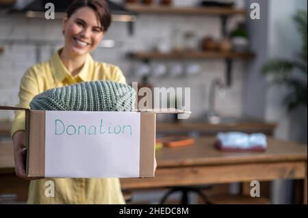 Sorridente volontario femminile che mostra le cose preparate per la donazione Foto Stock