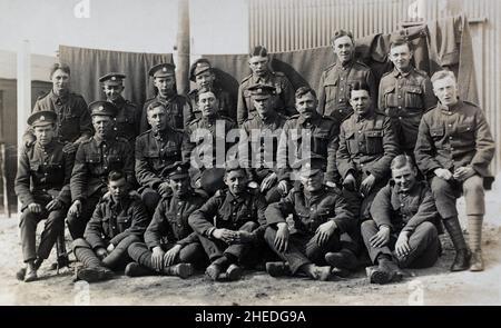 Un gruppo di soldati dell'esercito britannico dell'era della prima guerra mondiale nel reggimento del Devonshire in un campo militare. Due dei soldati seduti in prima fila sono soldati territoriali, indicati dalla 'T' sulle loro spalle. Gli altri hanno un mix di metallo e stoffa 'Devonshire' con il titolo di spalla. Foto Stock