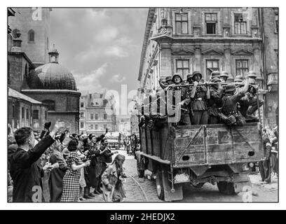 LVIV UCRAINA 1940s WW2 occupazione nazista in Germania a Lviv Ucraina. I civili accolgono l'esercito tedesco mentre entrano in città. In primo piano, un camion militare con soldati e civili tedeschi, proprio accanto alla cattedrale latina - una delle chiese più antiche di Lviv. Lviv è una città dell'Ucraina occidentale, a circa 70 chilometri dal confine con la Polonia Foto Stock