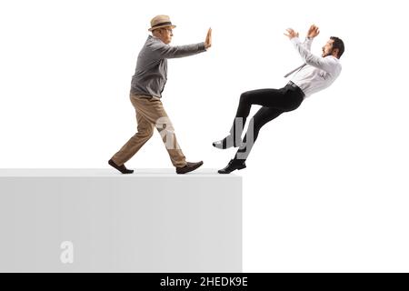 Colpo di profilo a tutta lunghezza di un uomo anziano che spinge un giovane uomo da un muro isolato su sfondo bianco Foto Stock