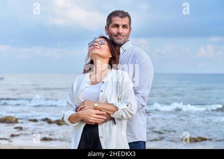 Ritratto all'aperto di coppia matura che abbraccia la riva del mare Foto Stock