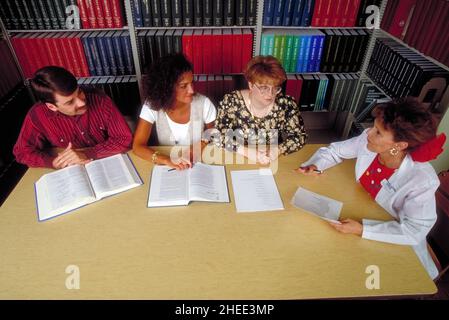 Springfield, Missouri, USA 16 settembre 1995: Gli studenti laureati si siedono con libri aperti in una biblioteca con un istruttore. Foto Stock