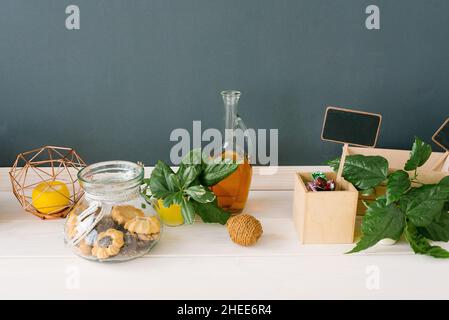 Biscotti in un vaso di vetro, una bottiglia di olio vegetale, candele e foglie verdi in cucina Foto Stock