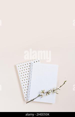 Un foglio bianco del taccuino con un rametto di mela bianca fiorisce su uno sfondo beige con spazio di copia Foto Stock