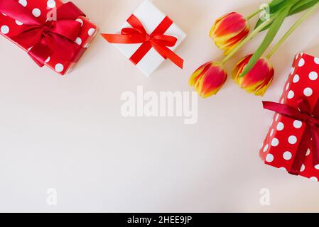 Sfondo romantico con bouquet di tulipani e confezioni regalo alla luce. Vista dall'alto con spazio di copia. Festa della mamma e San Valentino sfondo. Foto Stock