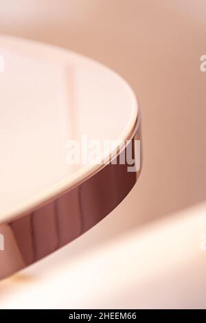 Alto angolo di tavolo rotondo con superficie riflettente in vetro e bordo dorato in casa Foto Stock