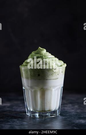 Bicchiere di caffè dalgona fresco con matcha posto sulla superficie grigia Foto Stock