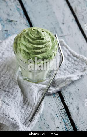 Da sopra un bicchiere di caffè dalgona fresco con matcha posto vicino alla paglia su tavola di legno Foto Stock