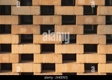 Un modello di pietre ruscello rosse che sono sfalsate e permettono alla luce di passare attraverso. Foto Stock