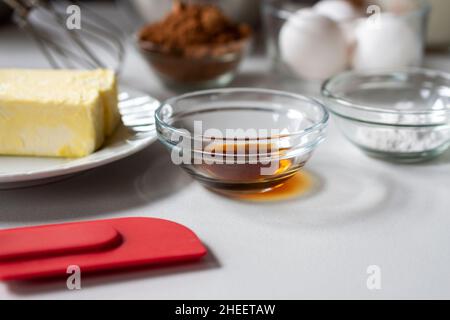 Vista laterale degli ingredienti di cottura. Gli ingredienti includono: Uova, burro, vaniglia, cacao e lievito in polvere. Foto Stock