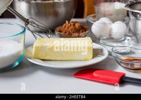 Ingredienti disposti prima della cottura. Gli ingredienti includono: Uova, latte, cacao, burro e lievito in polvere. Foto Stock