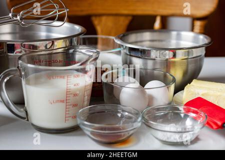 Ingredienti disposti prima della cottura. Gli ingredienti includono: Uova, latte, cacao, burro e lievito in polvere. Foto Stock