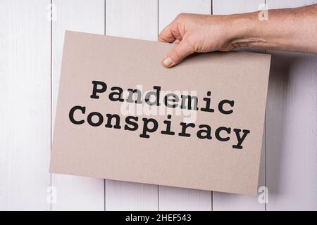 Un segno con le parole cospirazione pandemica tenuto in mano Foto Stock