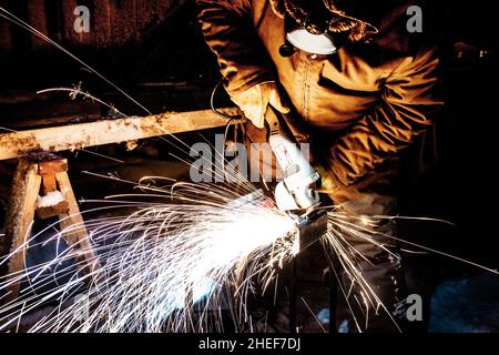 Lavoratrice che macina il metallo in inverno e al buio Foto Stock