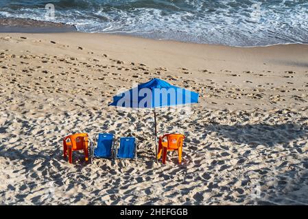 Ombrellone e sedie sulla spiaggia nel sole forte del giorno. Spiaggia di Paciencia a Salvador, Bahia, Brasile. Foto Stock