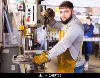 Artigiano che lavora su una macchina per la perforazione di strutture metalliche Foto Stock