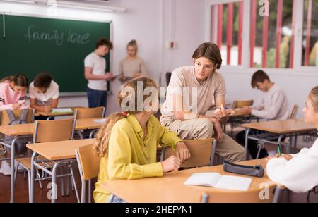 Gli allievi delle scuole adolescenti parlano durante la pausa in classe Foto Stock