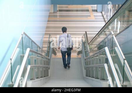 Uomo che scende le scale di un edificio moderno. Andare a casa dal lavoro o dal concetto di vita urbana. Foto Stock