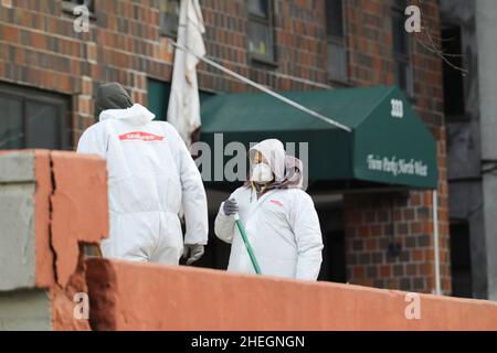 New York, Stati Uniti. 10th Jan 2022. I lavoratori ripuliscono all'esterno dell'edificio residenziale danneggiato da un grande incendio nel quartiere Bronx di New York City, Stati Uniti, 10 gennaio 2022. Secondo Eric Adams, il bilancio delle vittime di un grande incendio in un alto edificio nel quartiere Bronx di New York City è stato rivisto fino al 17 dal 19. Credit: Wang Ying/Xinhua/Alamy Live News Foto Stock