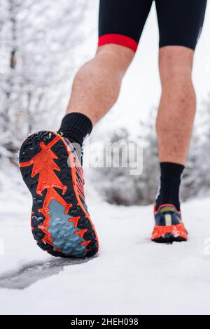 uomo sconosciuto che corre nella neve in inverno primo piano su scarpe da ginnastica Foto Stock