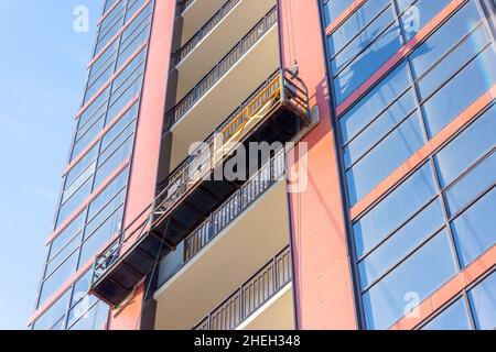 Ascensore sospeso su un alto edificio residenziale in costruzione, decorazione della facciata e finestre Foto Stock