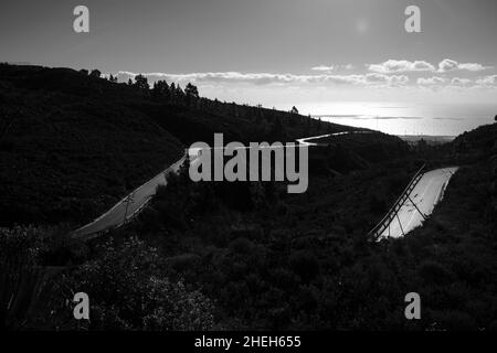 Superficie stradale illuminata bagnata con vista sulla costa di Granadilla da Las Vegas, Tenerife, Isole Canarie, Spagna Foto Stock