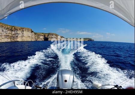 Vista fisheye del sentiero poppa di motoscafi sull'acqua di mare e le scogliere dell'isola di Gozo a Malta in giorno luminoso Foto Stock