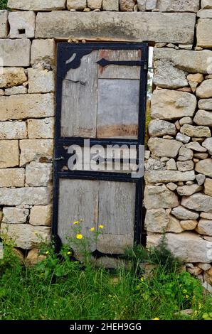 Porta di legno nell'antica parete di pietra Foto Stock