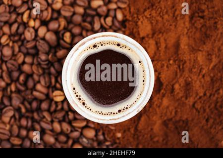 Tazza di caffè nero al centro del caffè fatto sfondo - metà in grano mezzo in polvere, immagine vista dall'alto. Foto Stock