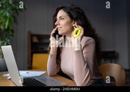 Giovane donna d'affari che fa esercitazioni di riscaldamento a mano sul posto di lavoro, esercitandosi con anello di rinforzo di presa Foto Stock