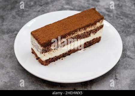 porzione di torta tiramisù su sfondo scuro. Prelibatezze della cucina tradizionale del mondo. Primo piano. Foto Stock