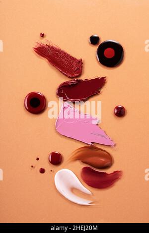 Le macchie di diversi colori sono realizzate con vari prodotti cosmetici. Su sfondo color pesca. Trama di tratti multicolore. Foto Stock