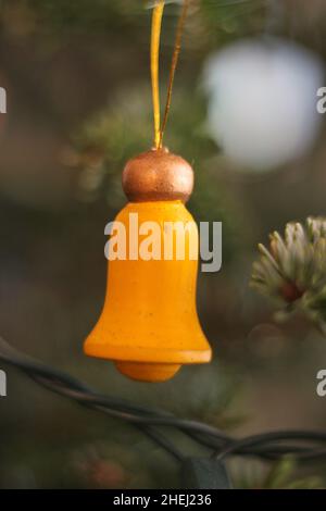 Campana di legno giallo brillante appesa sull'albero come ornamento di albero di Natale. Foto Stock