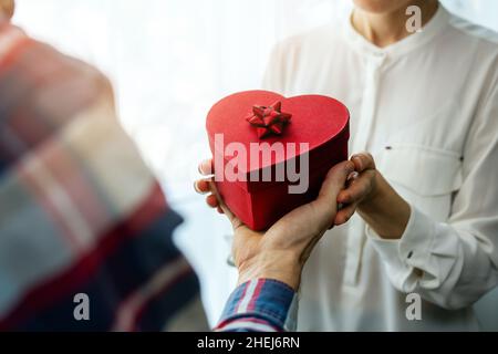 san valentino. uomo che dà romantico cuore scatola regalo alla sua donna. coppia innamorata Foto Stock