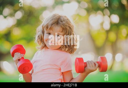 Allenamento per bambini. Bambini che si allenano con i manubri. Bambino sportivo con manubri all'aperto. Sport per bambini. Allenamento dei ragazzi nel parco. I bambini hanno uno stile di vita sano e attivo. Foto Stock