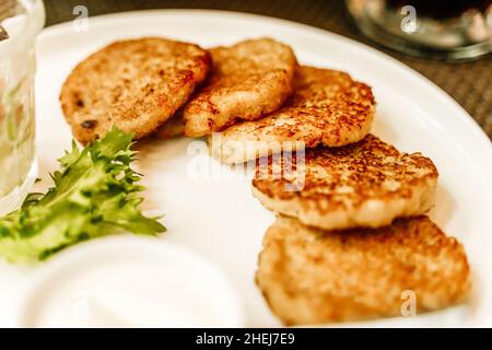 Frittelle di patate o draniki o lattkes su un piatto in un ristorante. Piatto tradizionale di patate e cibo in Europa orientale e Israele. Foto di alta qualità Foto Stock