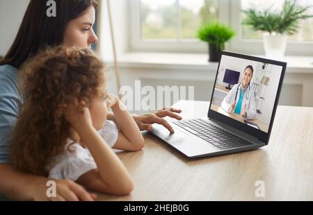 Madre e bambino guardando il video sulla medicina o avendo consultazione in linea con il medico Foto Stock