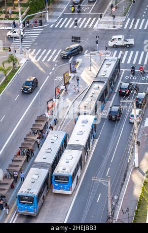 Autobus articolati su una trafficata autostrada urbana. Bus articolato BRT (Bus Rapid Transit) in una corsia bus BRT. Passeggeri alla fermata dell'autobus. San Paolo, Brasile Foto Stock