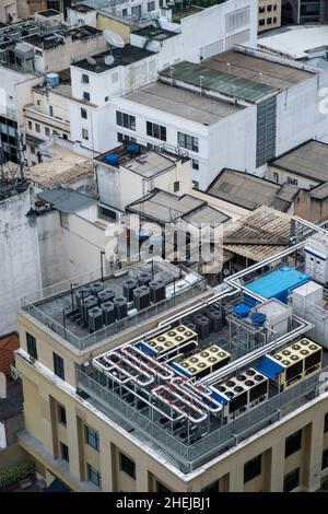 Unità di climatizzazione commerciali. Sfiati di scarico sul tetto di un alto edificio di uffici / appartamenti in un centro urbano occupato Foto Stock